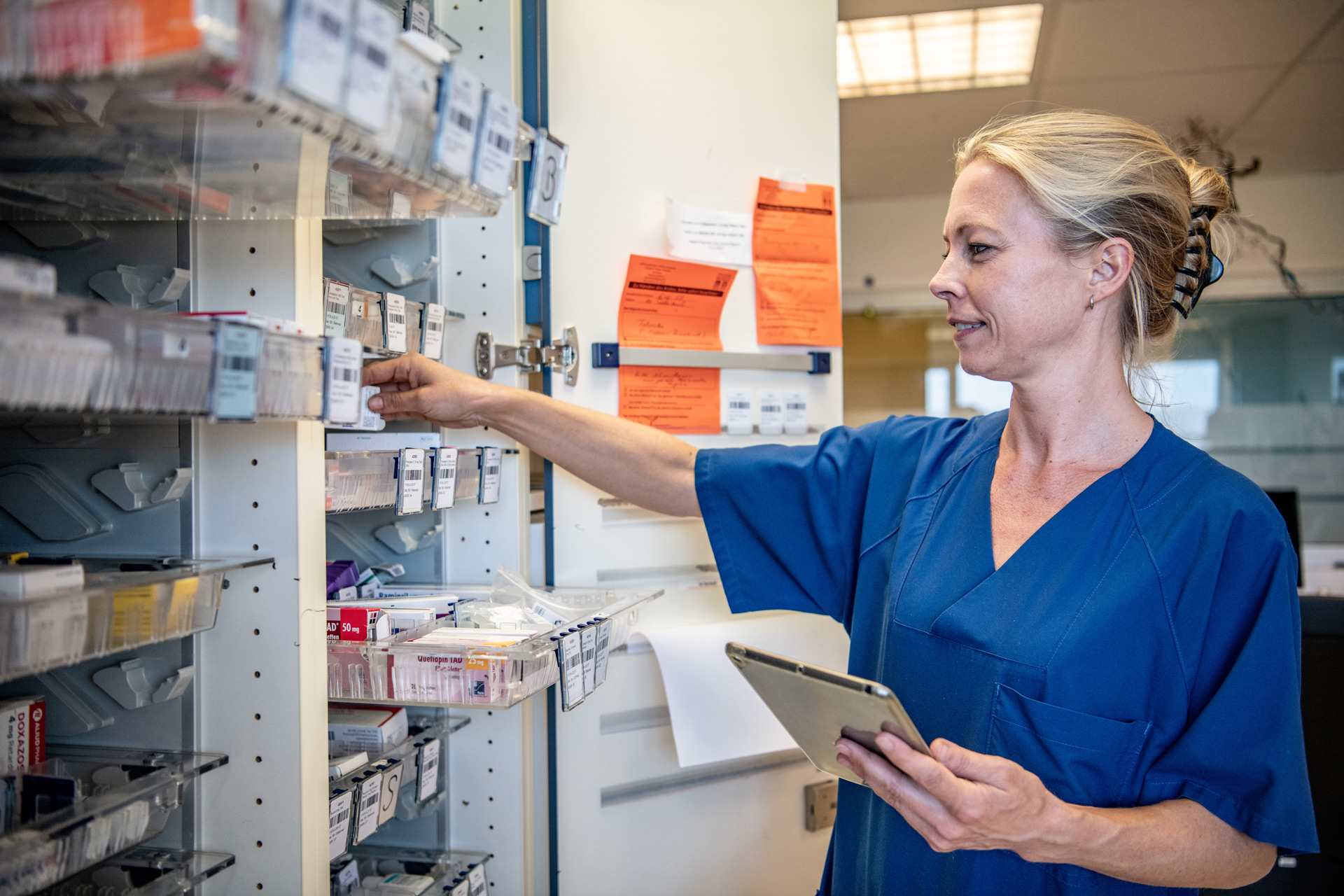 Krankenpflegerin an einem Medikamentenregal 
