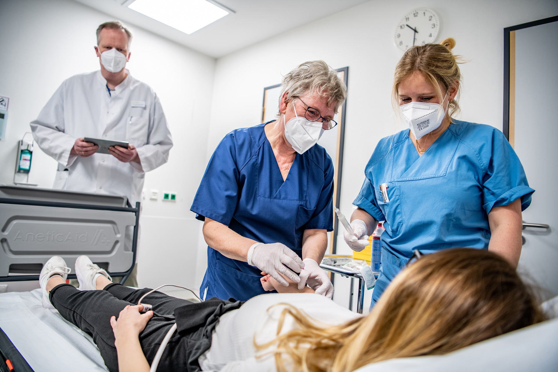 Zwei Krankenpflkegerinnen und ein Arzt behandeln eine Patientin